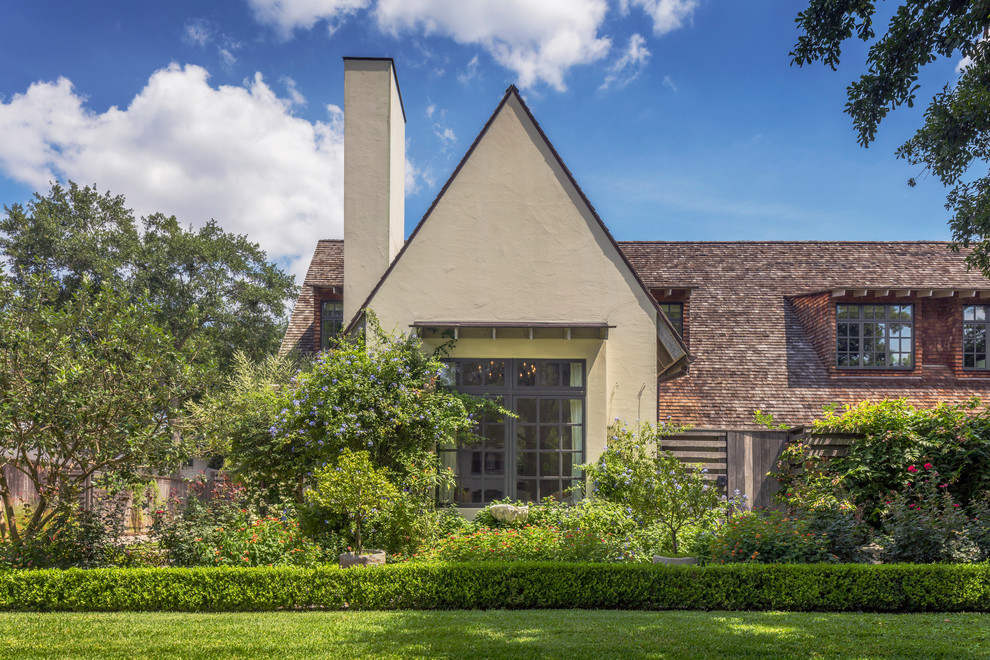 Imagen de fachada beige de estilo americano grande de dos plantas con revestimiento de estuco y tejado a dos aguas