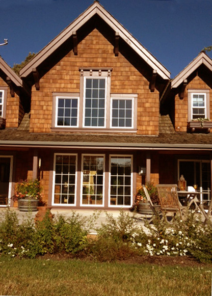 Immagine della facciata di una casa grande marrone country a due piani con rivestimento in legno