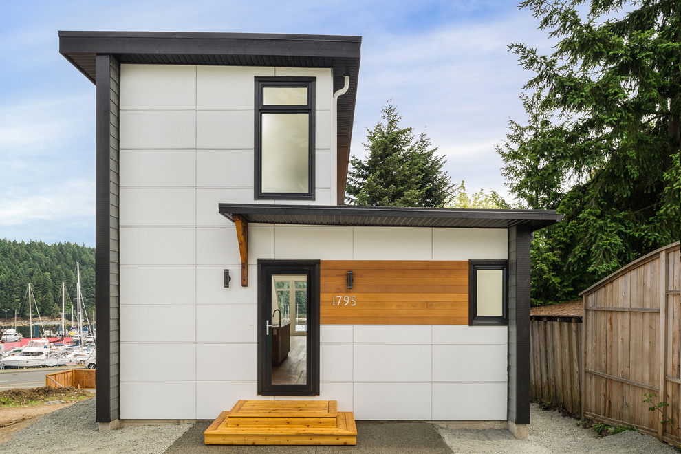 Esempio della facciata di una casa piccola bianca moderna a tre piani con rivestimento con lastre in cemento