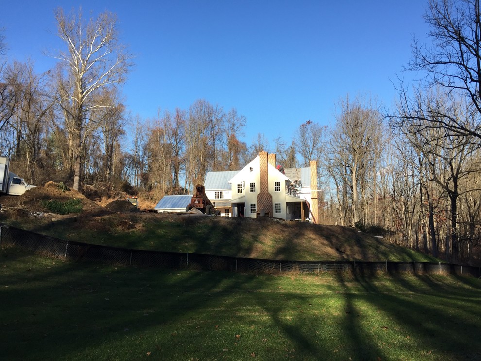 Foto della villa grande beige country a due piani con tetto a capanna e copertura in metallo o lamiera