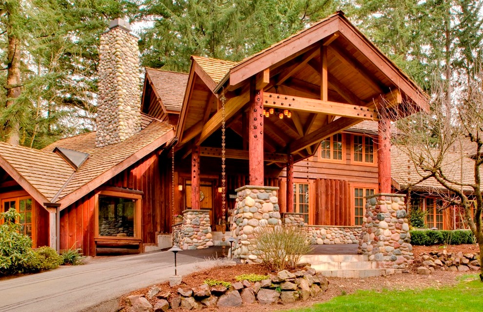 Cette image montre une grande façade de maison marron chalet en bois de plain-pied avec un toit à deux pans et un toit en shingle.