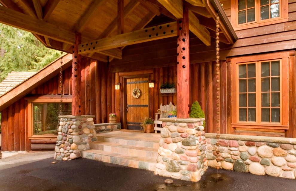 Foto della facciata di una casa grande marrone rustica a un piano con rivestimento in legno e tetto a capanna