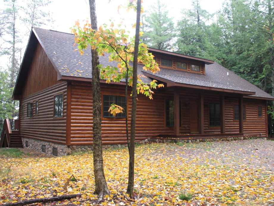 Réalisation d'une façade de maison marron chalet en bois de taille moyenne et à un étage avec un toit à deux pans et un toit en shingle.