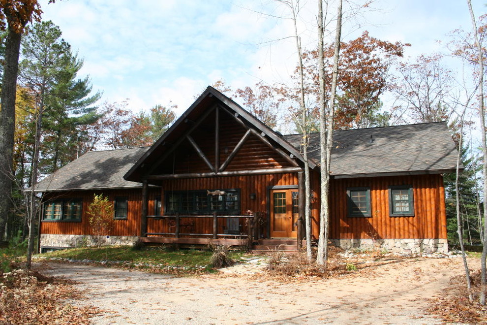 На фото: деревянный, коричневый, одноэтажный частный загородный дом среднего размера в стиле рустика с двускатной крышей и крышей из гибкой черепицы с