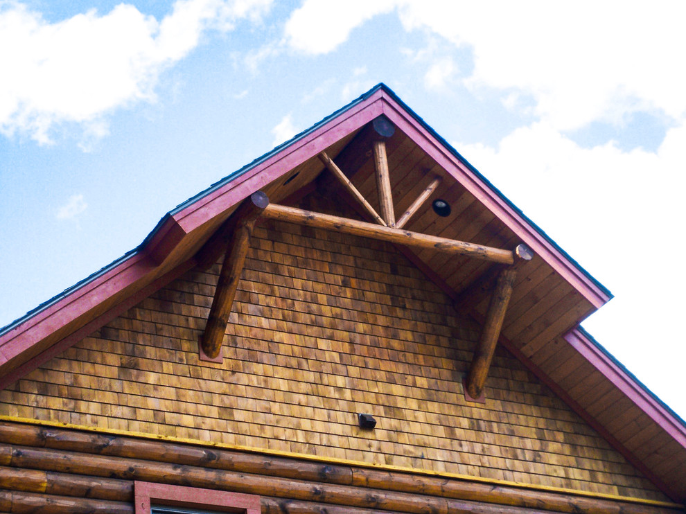 На фото: коричневый дом в стиле рустика с комбинированной облицовкой и двускатной крышей
