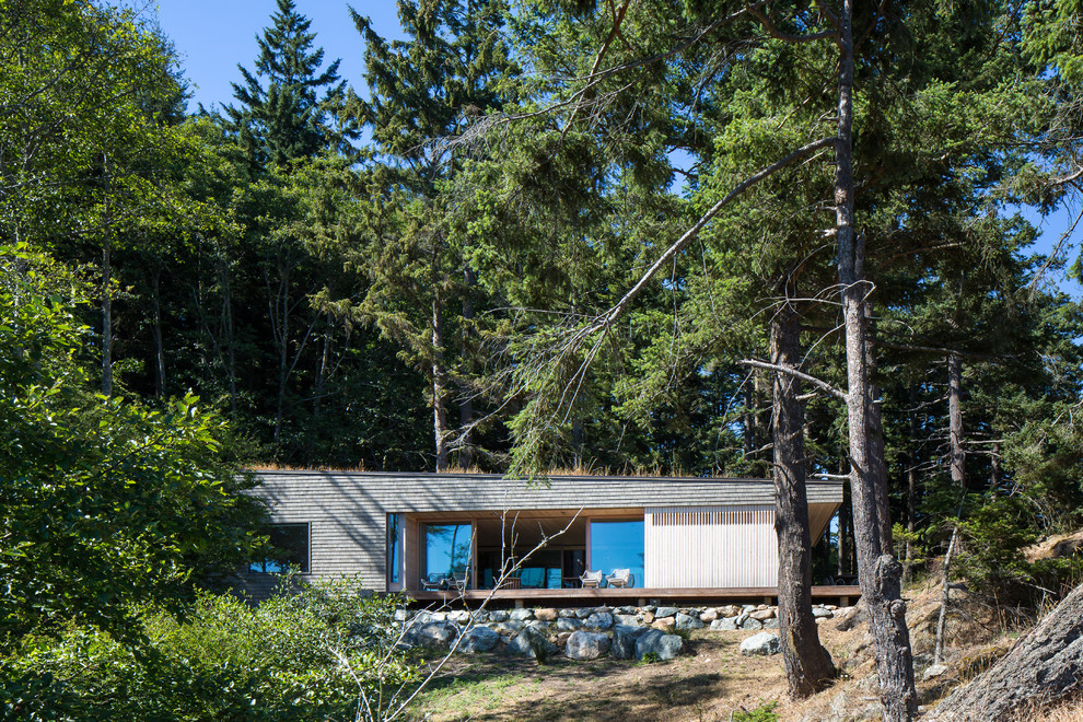 This is an example of a medium sized and gey modern bungalow house exterior in Seattle with wood cladding and a flat roof.