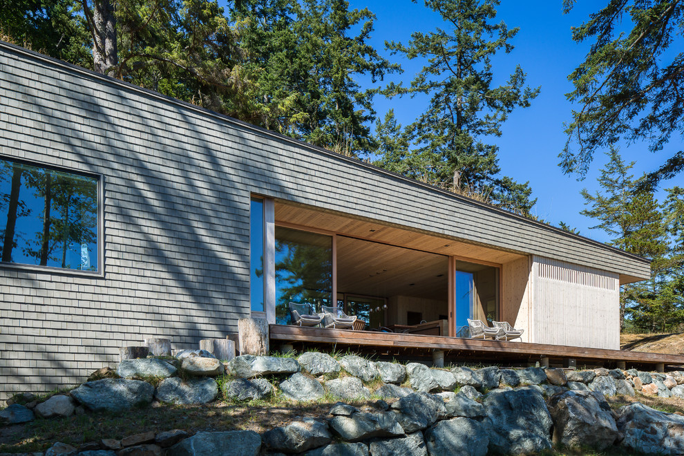 Стильный дизайн: одноэтажный, деревянный, серый дом среднего размера в стиле модернизм с плоской крышей - последний тренд