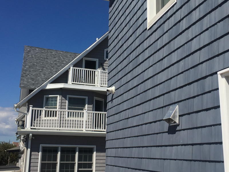 Réalisation d'une façade de maison bleue marine avec un revêtement en vinyle et un toit en shingle.