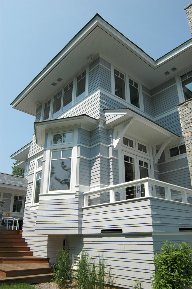 Exemple d'une très grande façade de maison grise chic en panneau de béton fibré à un étage avec un toit à quatre pans.