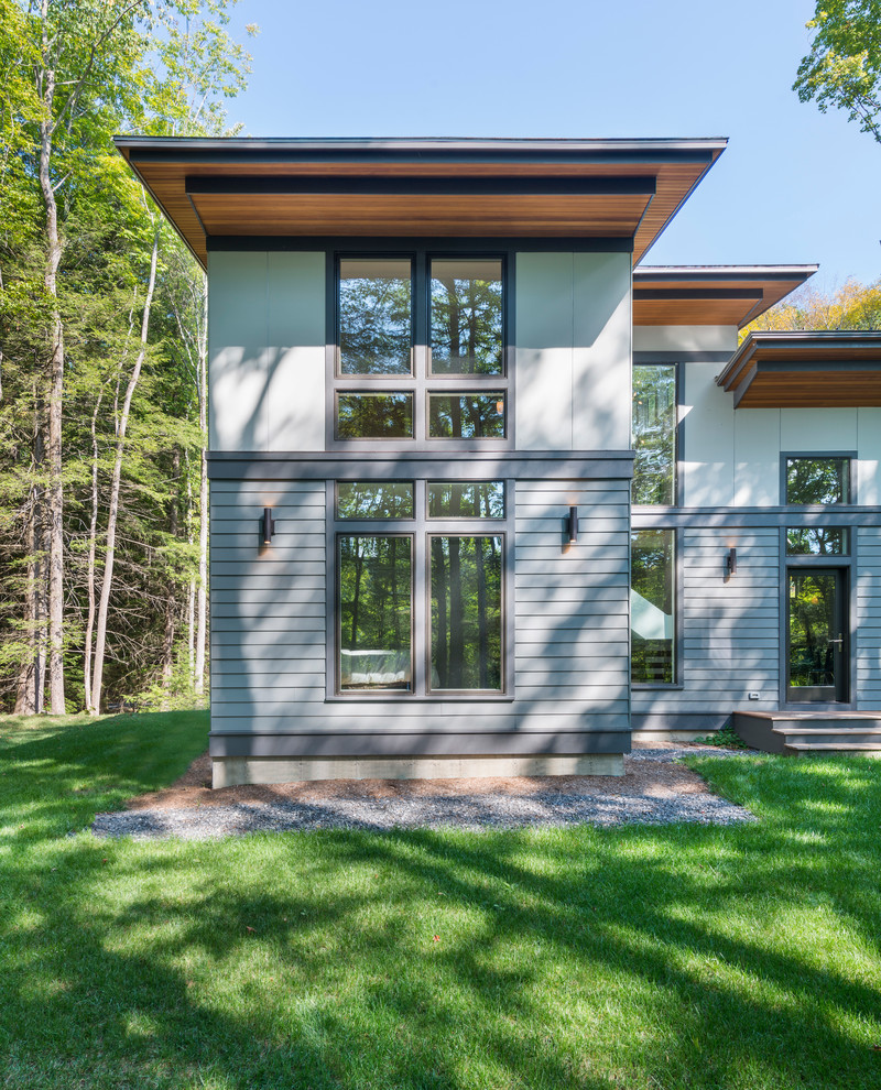 Inspiration pour une façade de maison grise design en panneau de béton fibré à un étage et de taille moyenne avec un toit en appentis.