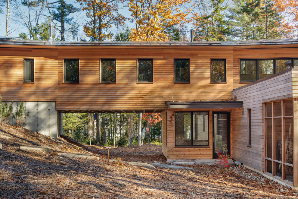 Exemple d'une façade de maison marron chic en bois à un étage avec un toit en appentis et un toit en métal.