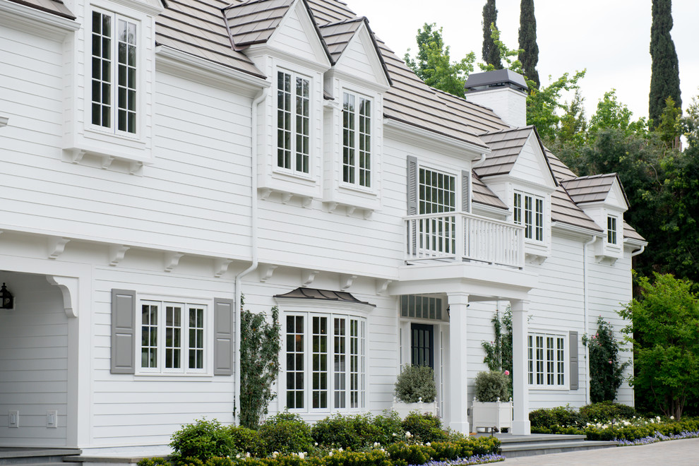 Inspiration for a large timeless white two-story exterior home remodel in Los Angeles with a clipped gable roof