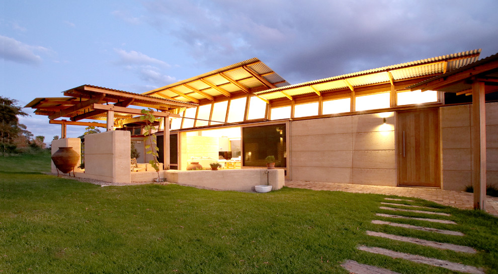 Ejemplo de fachada de casa minimalista grande de una planta con revestimiento de piedra, tejado plano y tejado de metal