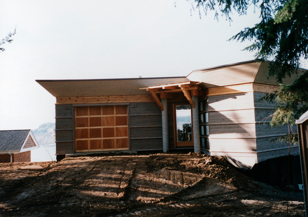 Diseño de fachada gris costera pequeña de dos plantas con revestimiento de madera y tejado plano