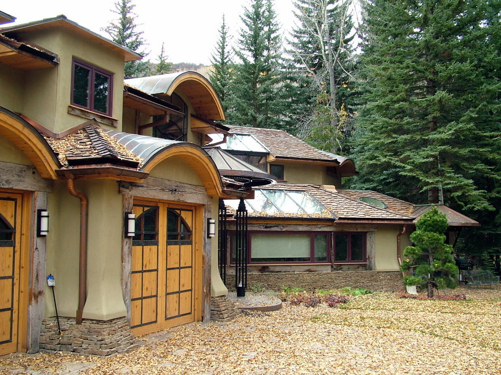 Example of a mid-sized eclectic green two-story stucco gable roof design in Denver