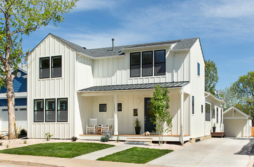 Esempio della facciata di una casa bianca country a due piani di medie dimensioni con rivestimento con lastre in cemento e tetto a capanna