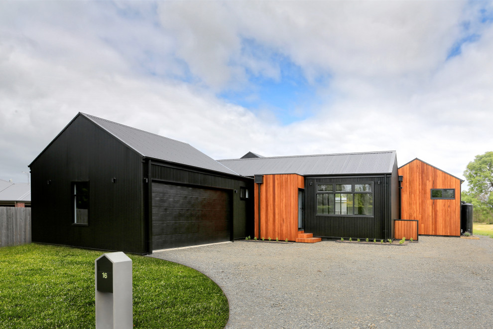Exempel på ett modernt svart hus, med blandad fasad, sadeltak och tak i metall