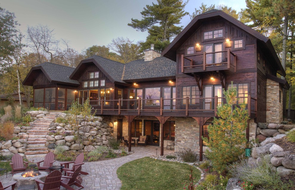 Cette photo montre une grande façade de maison marron montagne en bois à deux étages et plus avec un toit en shingle et un toit à croupette.