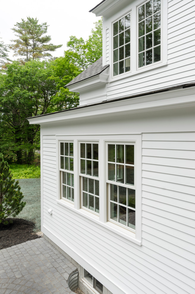 Modelo de fachada blanca de estilo de casa de campo de tamaño medio de dos plantas con revestimiento de madera