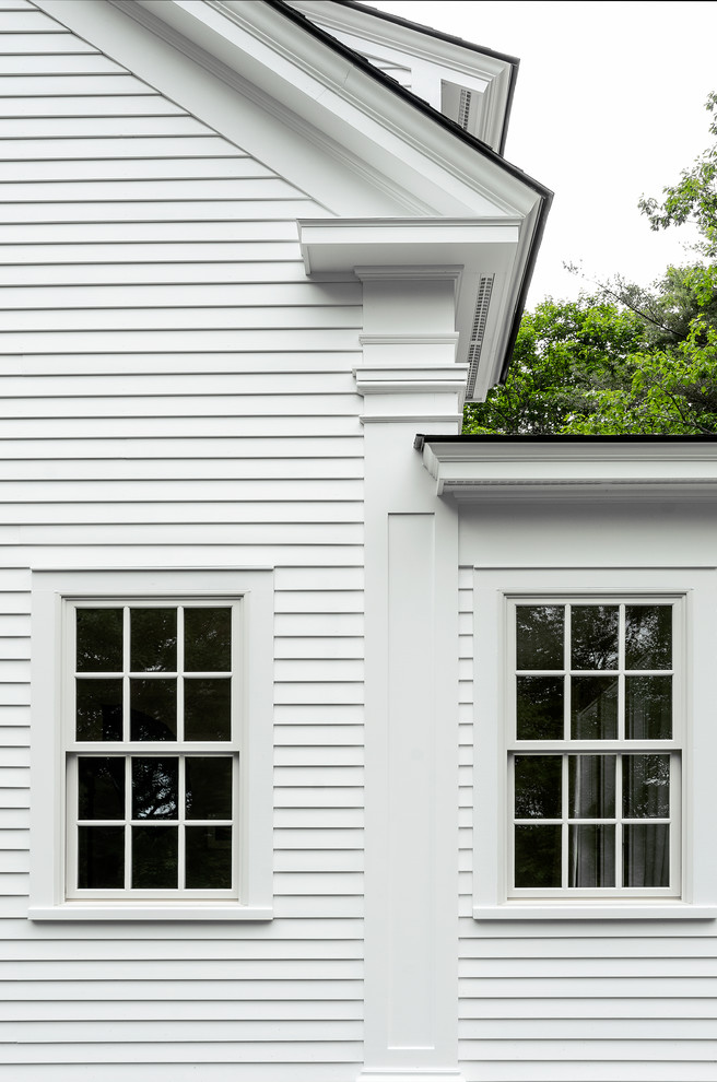 Foto della facciata di una casa bianca country a due piani di medie dimensioni con rivestimento in legno e tetto a capanna