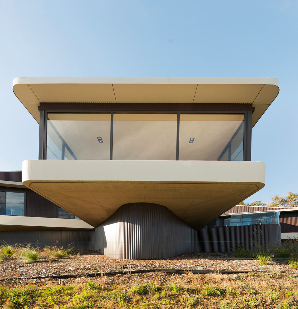 Foto della facciata di una casa beige contemporanea a due piani con rivestimento in vetro e tetto piano
