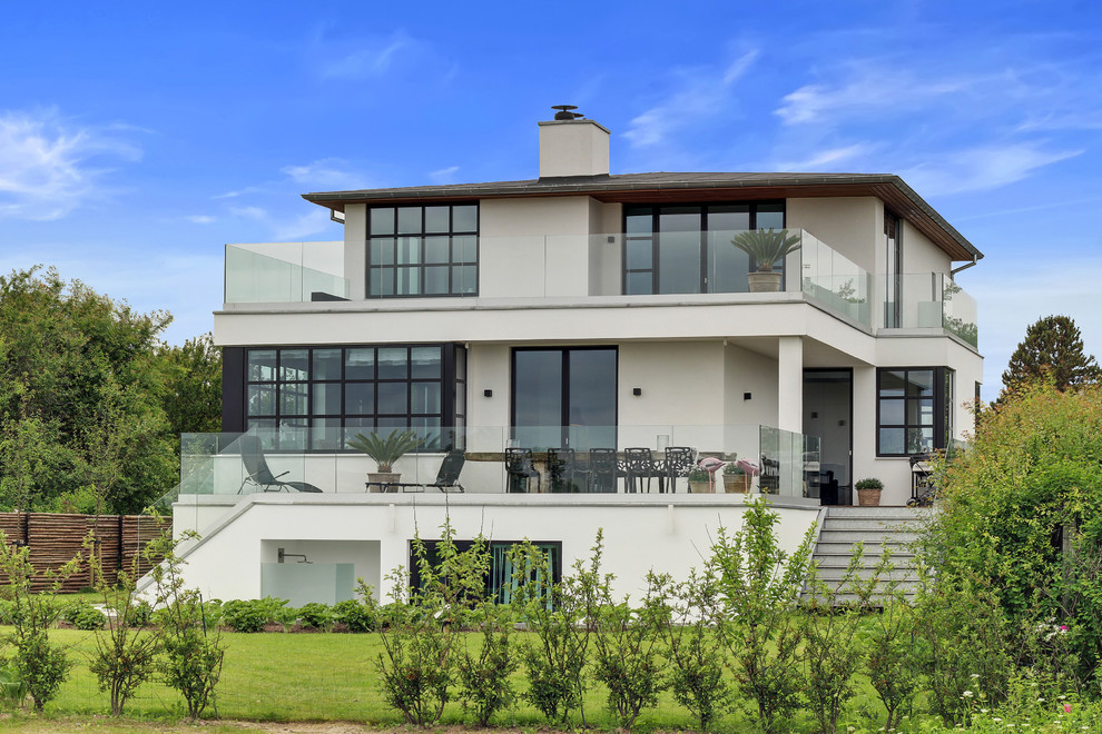 Idee per la facciata di una casa ampia beige contemporanea a due piani con rivestimento con lastre in cemento e tetto piano