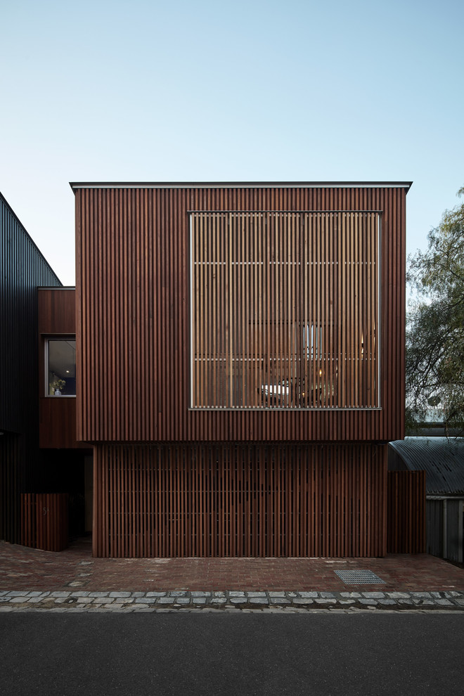 Diseño de fachada de casa marrón actual de tamaño medio de tres plantas con revestimiento de madera, tejado plano y tejado de metal