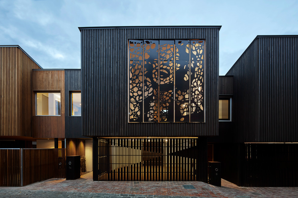 Foto della villa grande nera contemporanea a piani sfalsati con rivestimento in metallo, tetto piano e copertura in metallo o lamiera