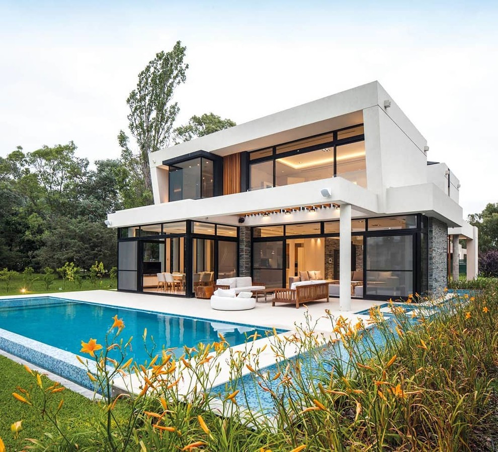 Cette image montre une grande façade de maison minimaliste à un étage avec un revêtement mixte et un toit à quatre pans.