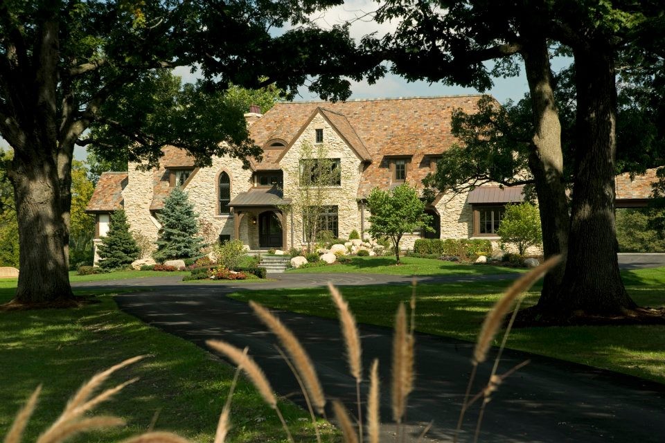 Cette image montre une très grande façade de maison beige craftsman en pierre à deux étages et plus avec un toit à quatre pans.