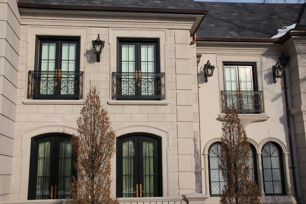 Aménagement d'une grande façade de maison grise classique en béton à un étage avec un toit à quatre pans.