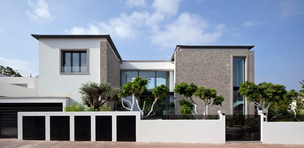 Aménagement d'une grande façade de maison blanche moderne en brique à un étage avec un toit plat.