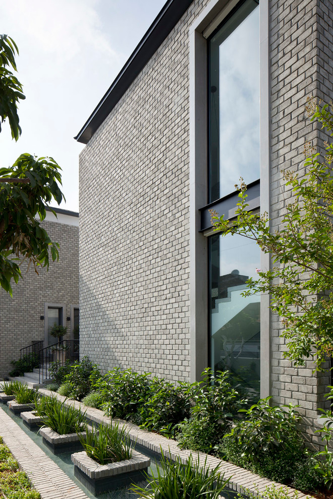 Aménagement d'une grande façade de maison blanche moderne en brique à un étage.