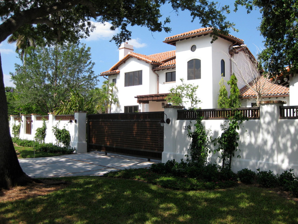 Foto della facciata di una casa grande bianca mediterranea a due piani con rivestimento in stucco e tetto a padiglione