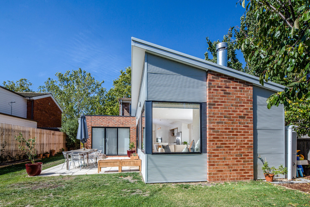 Пример оригинального дизайна: одноэтажный, серый частный загородный дом среднего размера в современном стиле с облицовкой из металла и односкатной крышей