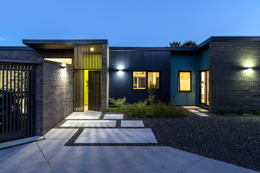 Réalisation d'une petite façade de maison grise design en brique de plain-pied avec un toit plat et un toit en métal.