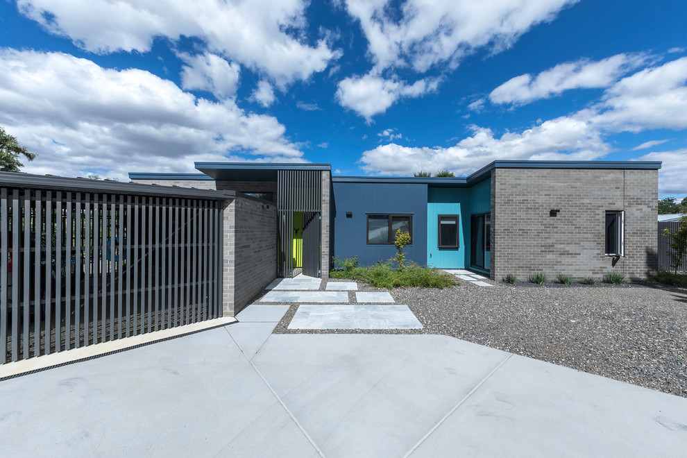 This is an example of a small and gey contemporary bungalow brick detached house in Canberra - Queanbeyan with a flat roof and a metal roof.