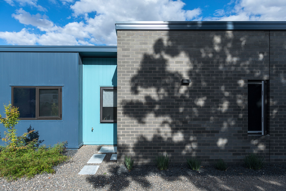 На фото: маленький, одноэтажный, кирпичный, серый частный загородный дом в современном стиле с плоской крышей и металлической крышей для на участке и в саду с