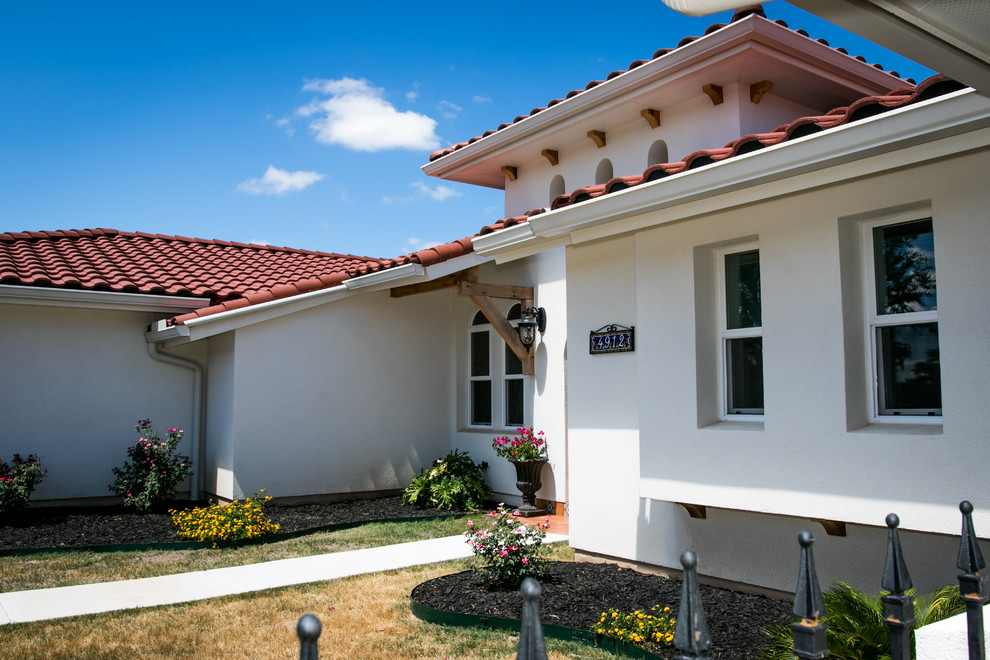 Photo of a large and white mediterranean bungalow render detached house in Austin with a hip roof and a tiled roof.