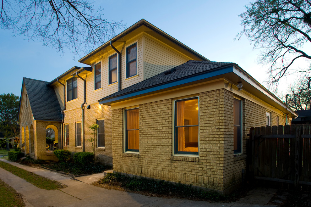 Imagen de fachada de casa amarilla y marrón clásica de dos plantas con revestimientos combinados