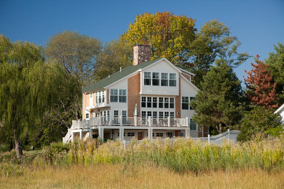 Immagine della villa bianca classica a tre piani con rivestimento in legno, tetto a capanna e copertura a scandole