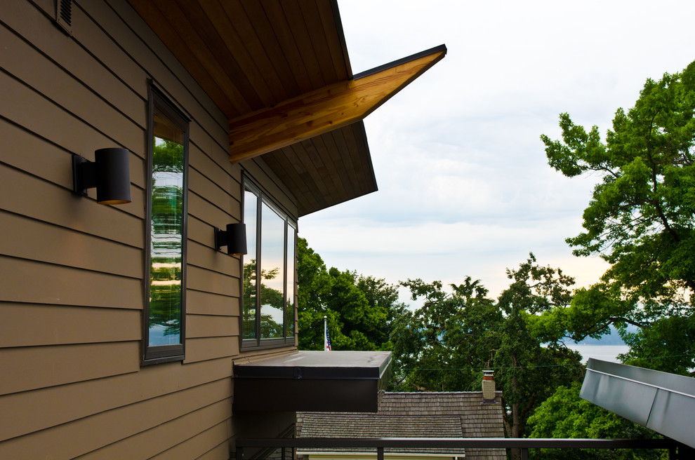 На фото: большой, трехэтажный, деревянный, коричневый дом в стиле модернизм с односкатной крышей с