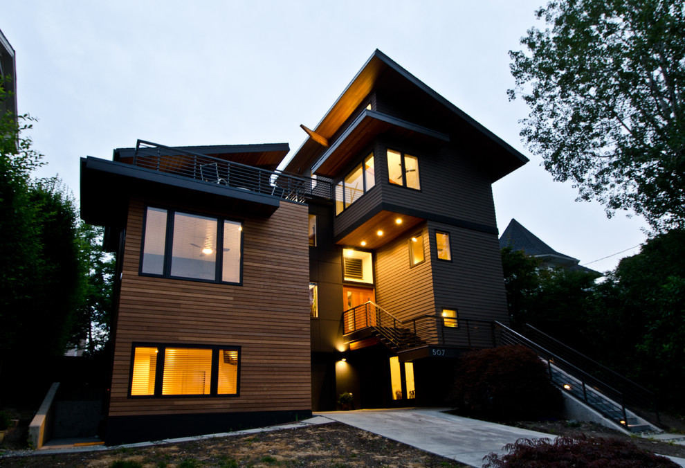 Cette photo montre une grande façade de maison verte moderne en bois à deux étages et plus avec un toit en appentis.