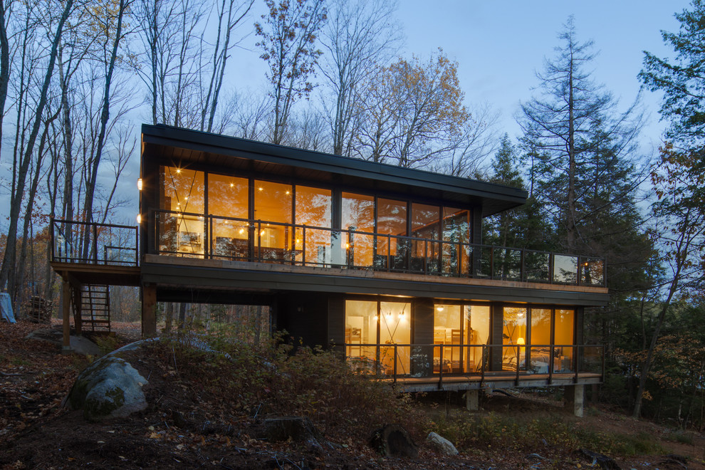 Idée de décoration pour une façade de maison marron minimaliste en verre de taille moyenne et à un étage avec un toit plat.