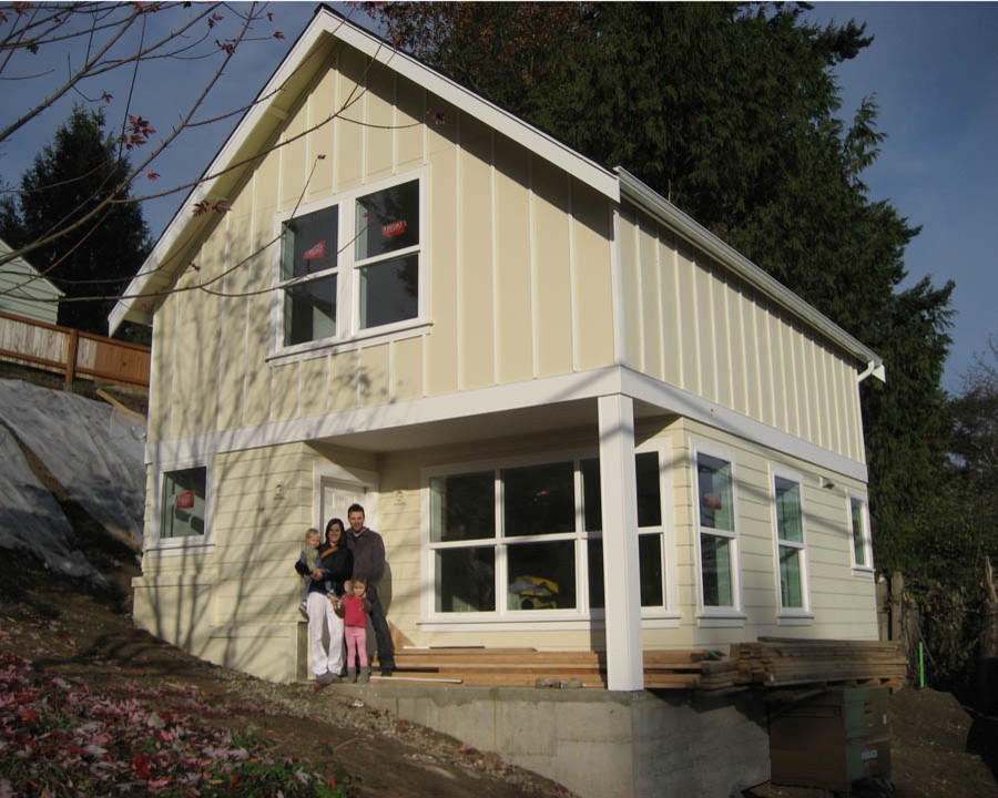 Стильный дизайн: маленький, двухэтажный, желтый дом с облицовкой из ЦСП и двускатной крышей для на участке и в саду - последний тренд