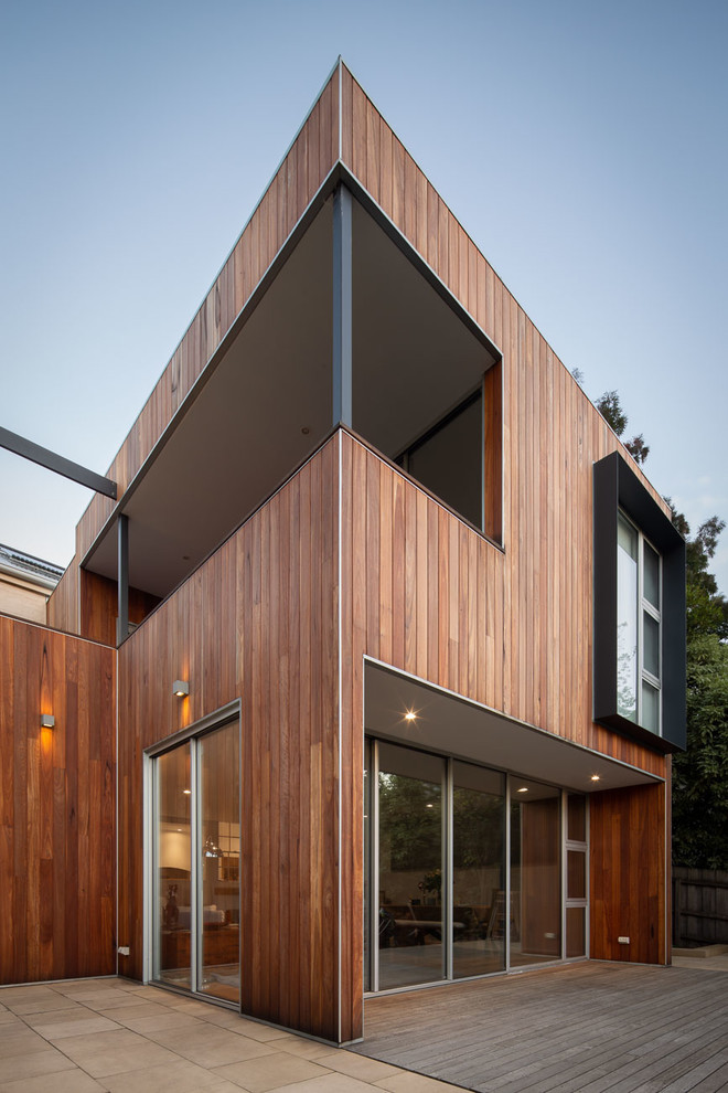 Cette image montre une façade de maison marron minimaliste en bois de taille moyenne et à un étage avec un toit plat et un toit en métal.