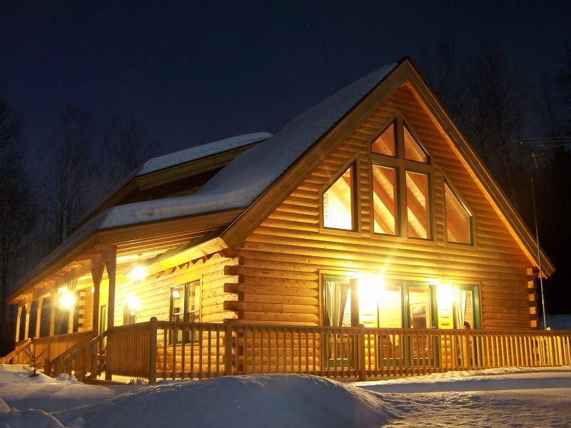 Idée de décoration pour une grande façade de maison marron chalet en bois à deux étages et plus avec un toit à croupette.