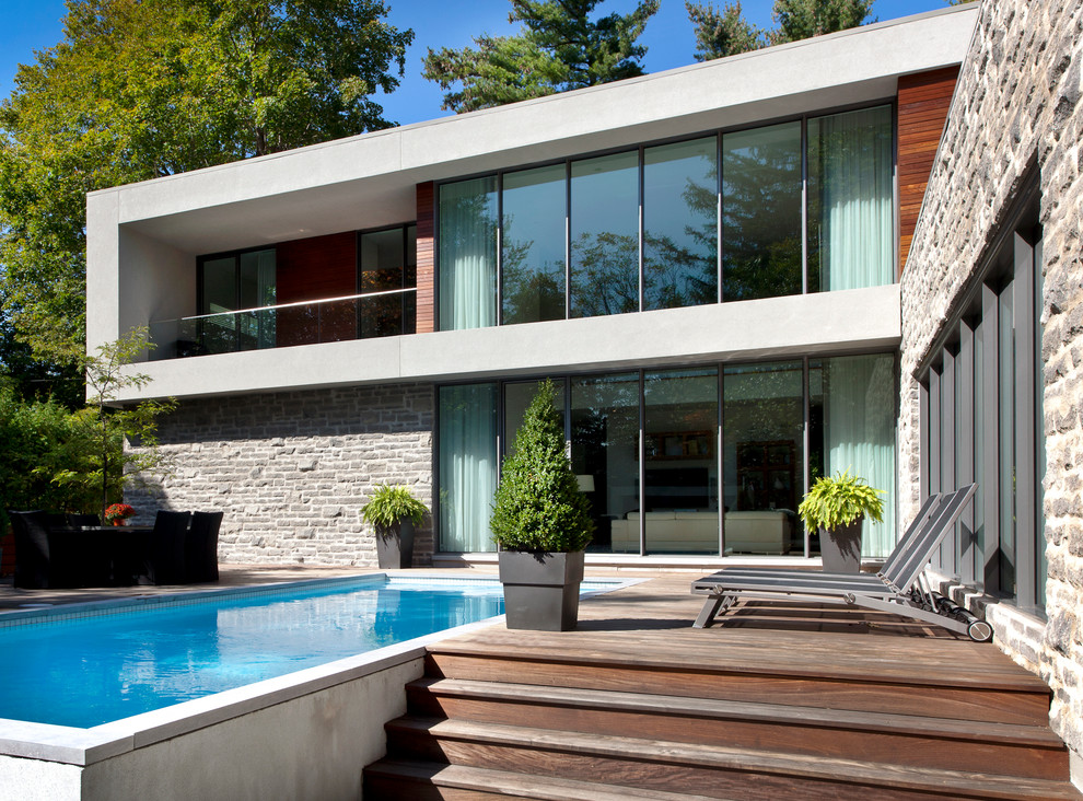 Inspiration for a modern two floor house exterior in Montreal with stone cladding and a flat roof.