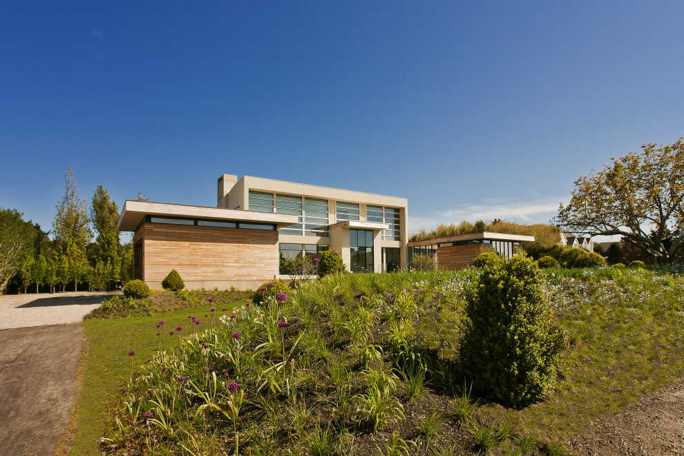 Immagine della villa beige moderna a due piani con rivestimento in legno, tetto piano e copertura in metallo o lamiera
