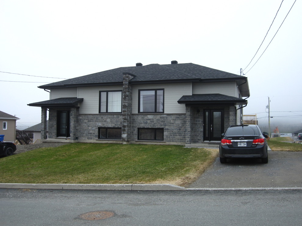 Cette image montre une petite façade de maison grise design de plain-pied avec un revêtement mixte et un toit à quatre pans.